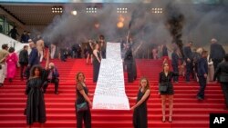 FILE - A banner is unveiled with a list of names that reads '129 feminicides since the last Cannes festival' at premiere of the film 'Holy Spider,' Cannes, France, May 22, 2022.