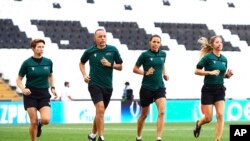 FILE - Assistant referee Michelle O'Neill of Ireland, fourth official Cuneyt Cakir of Turkey, main referee Stephanie Frappart of France and assistant referee Manuela Nicolosi, run during a training session at the Besiktas Park in Istanbul, Aug. 13, 2019.