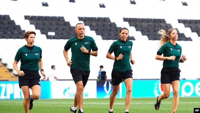 FILE - Assistant referee Michelle O'Neill of Ireland, fourth official Cuneyt Cakir of Turkey, main referee Stephanie Frappart of France and assistant referee Manuela Nicolosi, run during a training session at the Besiktas Park in Istanbul, Aug. 13, 2019.