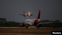 Un avión de Avianca Airlines aterriza mientras otro se prepara para despegar en el Aeropuerto Internacional San Oscar Arnulfo Romero en San Luis Talpa, El Salvador, el 8 de febrero de 2022. 