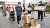 In this photo released by China's Xinhua News Agency, members of a COVID-19 testing team are greeted at an airport in Shanghai, China, as they prepare to return home to Hubei province, May 14, 2022.