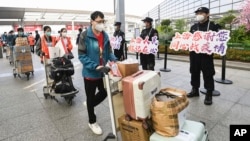 In this photo released by China's Xinhua News Agency, members of a COVID-19 testing team are greeted at an airport in Shanghai, China, as they prepare to return home to Hubei province, May 14, 2022.