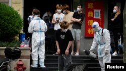 A worker in a protective suit disinfects a person during lockdown, amid the coronavirus disease (COVID-19) outbreak, in Shanghai, China, May 20, 2022.