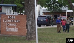 A welcome sign is seen outside of Robb Elementary School as people walk away in Uvalde, Texas, May 24, 2022.