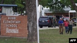 A welcome sign is seen outside of Robb Elementary School as people walk away in Uvalde, Texas, May 24, 2022.