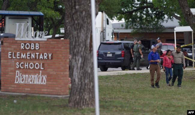 A welcome sign is seen outside of Robb Elementary School as people walk away in Uvalde, Texas, May 24, 2022.
