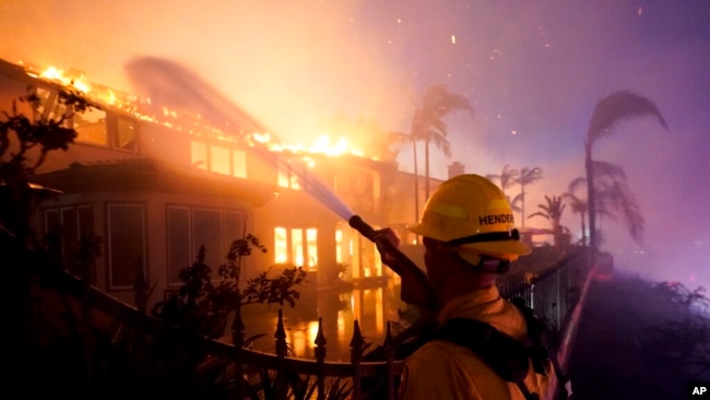 A firefighter works to put at a burning building during a wildfire May 11, 2022, in Laguna Niguel, Calif.