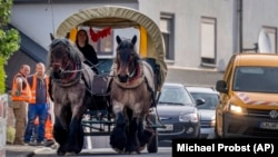 Horse farmer Stephanie Kirchner steers her coach on the main road through her hometown Schupbach near Limburg, Germany, May 19, 2022. (AP Photo/Michael Probst)