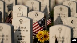 Batu nisan dihiasi dengan bendera Amerika di Leavenworth National Cemetery pada malam Memorial Day, Minggu, 29 Mei 2022, di Leavenworth, AS. (Foto: AP/Charlie Riedel)