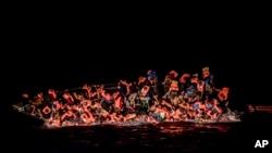 FILE: Dozens of migrants fall in the water while they struggle to cling to the side of an upturning boat off the waters of Tunisia, 5.25.2022