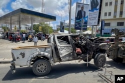 A destroyed vehicle is removed from the scene after a suicide bomb attack at a checkpoint near the airport in Mogadishu, Somalia, May 11, 2022.