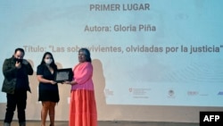 El camarógrafo mexicano Marco Gutiérrez, izq y la periodista mexicana Gloria Pina reciben el Premio Breach-Valdez de Periodismo y Derechos Humanos de manos de la viuda del periodista mexicano Javier Valdez, Griselda Triana, en Ciudad de México el 12 de mayo de 2022.
