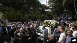 El padre del fiscal antidrogas asesinado Marcelo Pecci, Francisco Pecci, y amigos se abrazan antes de llevar los restos de su hijo a un velorio en la Iglesia del Colegio San José en Asunción, Paraguay, el domingo 15 de mayo de 2022. (Foto AP/Jorge Sáenz)