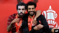Liverpool's Thiago, wearing a mask of Mohamed Salah, embraces Salah after they won the English FA Cup final football match, May 14, 2022.