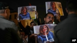 Protesters hold photos of slain Al Jazeera journalist Shireen Abu Akleh as they shout at Israeli border police in Haifa, Israel, May 11, 2022. Abu Akleh was shot and killed on Wednesday while covering an Israeli military raid in the occupied West Bank.
