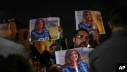 Protesters hold photos of slain Al Jazeera journalist Shireen Abu Akleh as they shout at Israeli border police in Haifa, Israel, May 11, 2022. Abu Akleh was shot and killed on Wednesday while covering an Israeli military raid in the occupied West Bank.