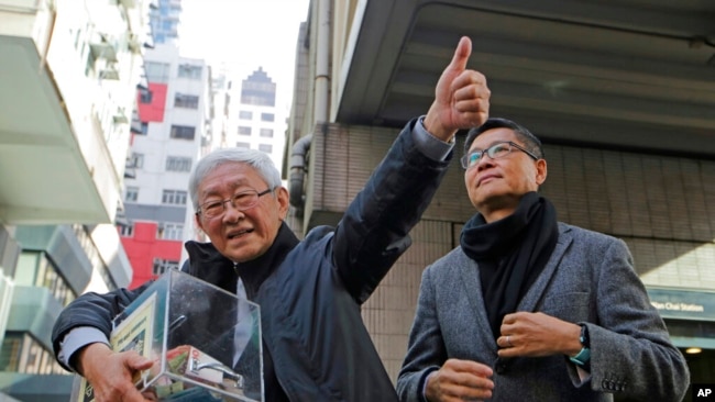 FILE - Retired archbishop of Hong Kong Cardinal Joseph Zen, left, holds a donation box during an annual New Year protest in Hong Kong, on Jan. 1, 2019.
