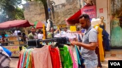 Workers at pavement stalls in a busy market have no place to shelter from the heat. (Anjana Pasricha/VOA)