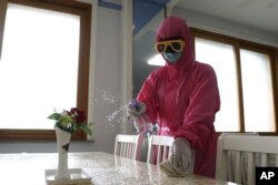 FILE - An employee of Pyongyang Dental Hygiene Products Factory disinfects the floor of a dinning room as the state increased measures to stop the spread of illness in Pyongyang, North Korea, May 16, 2022.