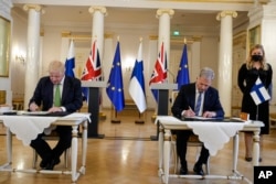 British Prime Minister Boris Johnson, left, and Finland's President Sauli Niinisto sign a security assurance, at the Presidential Palace in Helsinki, Finland, May 11, 2022. (AP Photo/Frank Augstein, Pool, File)