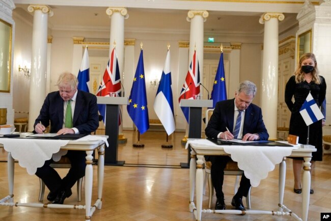 British Prime Minister Boris Johnson, left, and Finland's President Sauli Niinisto sign a security assurance, at the Presidential Palace in Helsinki, Finland, May 11, 2022. (AP Photo/Frank Augstein, Pool, File)