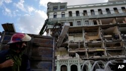 An emergency worker looks at the damage from Friday's deadly explosion that destroyed the five-star Hotel Saratoga, in Havana, Cuba, May 7, 2022. 