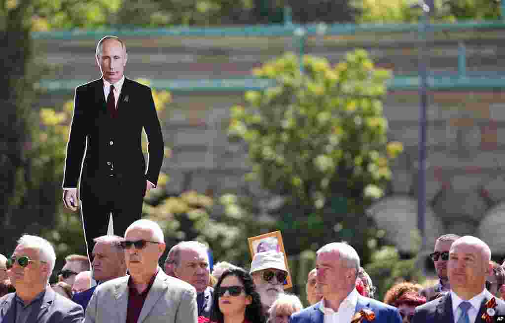 A man holds a picture of Russian President Vladimir Putin during the Victory Day ceremony in Belgrade, Serbia.