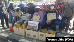 Aksi membeton atau mengecor kaki dilakukan oleh tiga petani desa Peura dan Tonusu Kabupaten Poso alam aksi protes di depan Kantor Gubernur Sulawesi Tengah di Palu, pada 24 Mei 2022.(Foto: VOA/Yoanes Litha). 