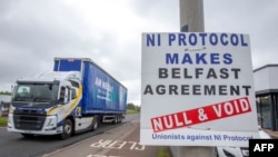 A truck passes an anti 'Northern Ireland Protocol' sign as it is driven away from Larne port, north of Belfast in Northern Ireland, after arriving on a ferry, May 17, 2022. 