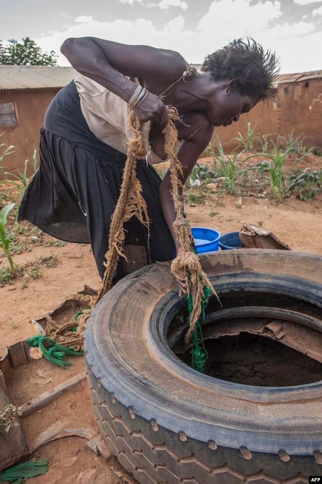 FILE - A woman draws water from an unprotected well at Kawondo in Area 36, in Lilongwen, Malawi, Jan. 25, 2018.