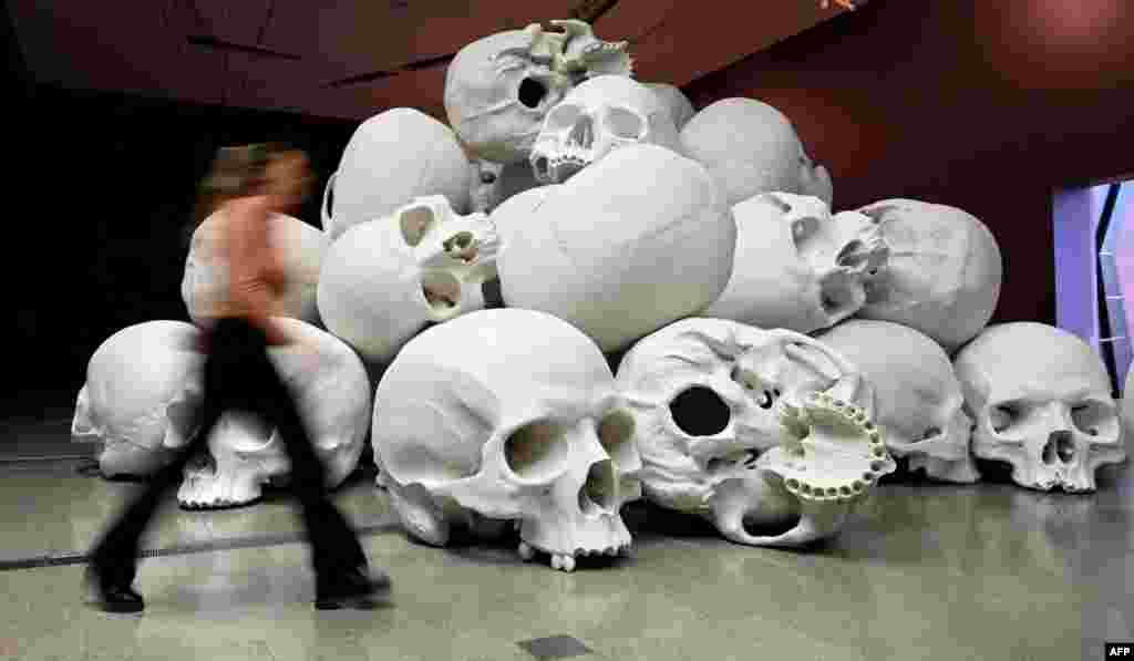 A person looks at Australian artist Ron Mueck&#39;s large-scale installation &#39;Mass&#39; which comprises more than 100 hand-cast skulls that collectively weigh approximately 5000 kilograms at an exhibition at the National Gallery of Victoria in Melbourne.