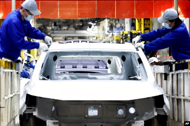 FILE - In this photo released by China's Xinhua News Agency, laborers work at the assembly workshop of automaker SAIC Motor Company's Lingang base in Shanghai, April 23, 2022. (Chen Jianli/Xinhua via AP, File)