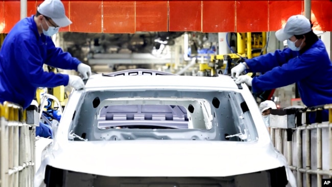 FILE - In this photo released by China's Xinhua News Agency, laborers work at the assembly workshop of automaker SAIC Motor Company's Lingang base in Shanghai, April 23, 2022.