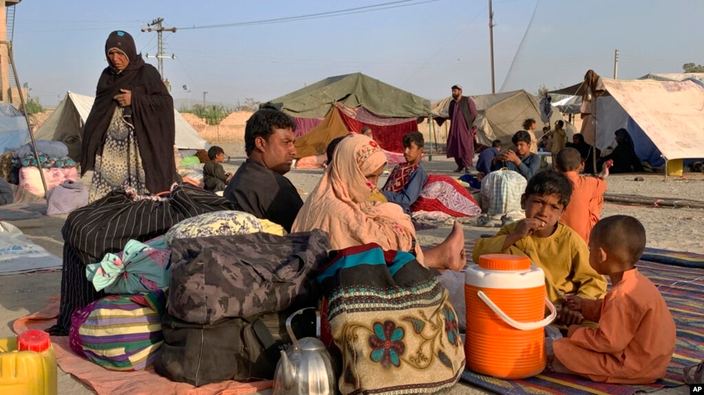 FILE - Afghan families sit outside their tents in an open area on the outskirts of Chaman, a border town in the Pakistan's southwestern Baluchistan province, Aug. 31, 2021. 