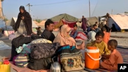FILE - Afghan families sit outside their tents in an open area on the outskirts of Chaman, a border town in the Pakistan's southwestern Baluchistan province, Aug. 31, 2021. 