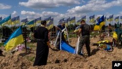 Undertakers lower the coffin of Ukrainian serviceman Oleksander Matyukhin, 32, in Kharkiv, eastern Ukraine, Monday, May 23, 2022. (AP Photo/Bernat Armangue)