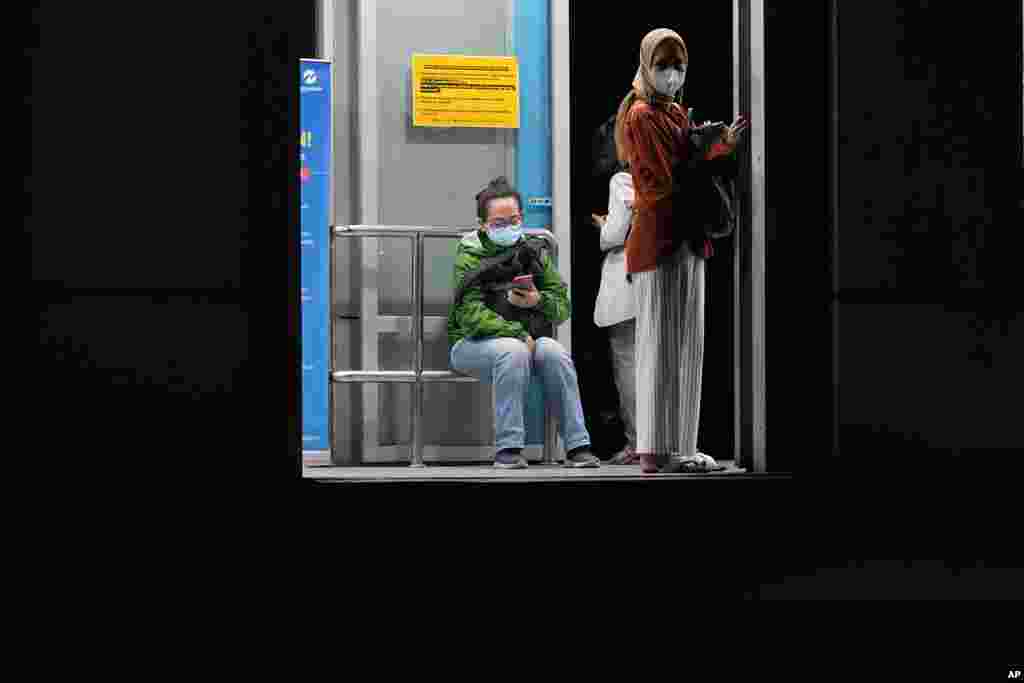 People wearing masks to slow the spread of the coronavirus wait at a bus stop in Jakarta, Indonesia. Indonesia will lift its outdoor mask requirement because its COVID-19 outbreak appears to be slowing, President Joko Widodo said.