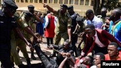 Ugandan police officers detain students marching toward parliament to protest against the major rise in the cost of raw materials, in Kampala.