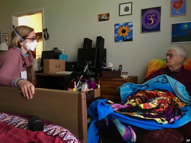 Rev. Jo Laurence, a Buddhist chaplain, speaks about meditation and bodily suffering with hospice patient Skylar Freimann on April 20, 2022 at an assisted living facility in Portland, (AP Photo/Gosia Wozniacka)