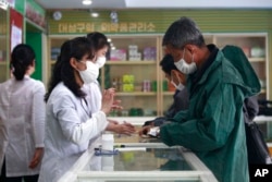 Employees of the Medicament Management Office of the Daesong District in Pyongyang provide medicine to residents as the state increases measures to stop the spread of illness in Pyongyang, North Korea, Monday, May 16, 2022. (AP Photo/Jon Chol Jin)