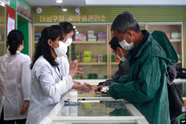 Employees of the Medicament Management Office of the Daesong District in Pyongyang provide medicine to residents as the state increases measures to stop the spread of illness in Pyongyang, North Korea, Monday, May 16, 2022. (AP Photo/Jon Chol Jin)