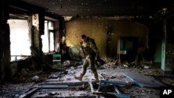 A Ukrainian serviceman inspects a school damaged during a battle between Russian and Ukrainian forces in the village of Vilkhivka, on the outskirts of Kharkiv, in eastern Ukraine, May 20, 2022. 