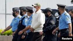 Oficiales de policía escoltan al exjefe de policía hondureño Juan Carlos 'El Tigre' Bonilla, quien está siendo extraditado a los Estados Unidos por cargos de narcotráfico, en Tegucigalpa, Honduras, el 10 de mayo de 2022.