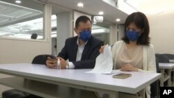 Jason Ding at left and Nancy Chen look over paperwork for national compensation case at a meeting for families who lost their loved ones to COVID-19 on Sept. 17, 2021, Taipei, Taiwan.
