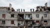 Workers clean rubbles atop a buidling destroyed by shelling a month ago in Cherkaske, eastern Ukraine on May 11, 2022. 
