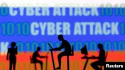 ແຟ້ມພາບ - ຮູບພາບຂອງຄົນໃຊ້ຄອມພິວເຕີແລະໂທລະສັບມືຖືຢູ່ນັ້ນ ແມ່ນເຫັນໄດ້ຢູ່ດ້ານໜ້າ ຂອງຂໍ້ຄວາມທີ່ວ່າ "ການໂຈມຕີທາງໄຊເບີ ຫຼື 'Cyber Attack', ພ້ອມດ້ວຍລະຫັດຄອມພິວເຕີ ແລະທຸງຊາດຂອງຣັດເຊຍ, ໃນພາບຕົວຢ່າງນີ້ ທີ່ໄດ້ຖືກຖ່າຍໄວ້ ເມື່ອວັນທີ 15 ກຸມພາ 2022. 