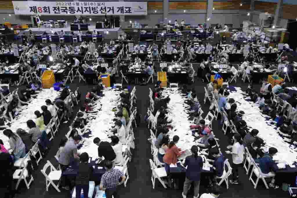 South Korean National Election Commission officials go through ballots for counting at the local elections to elect mayors, governors, council members and education superintendents nationwide at a gymnasium in Seoul.