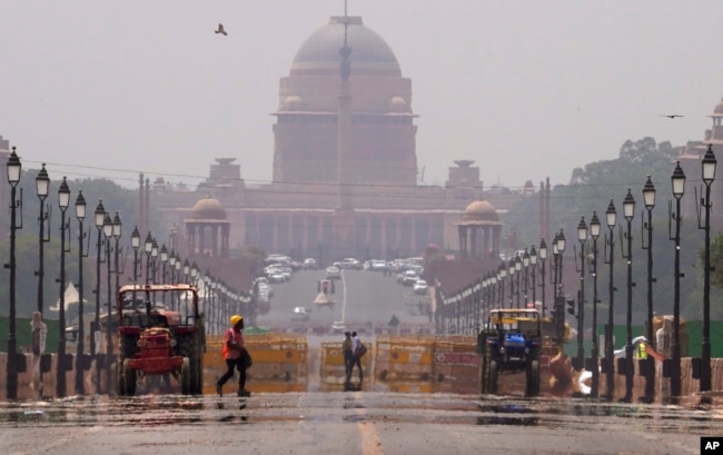 FILE - A construction worker walks across a road during a heat wave, in New Delhi, May 2, 2022. (AP Photo/Manish Swarup)