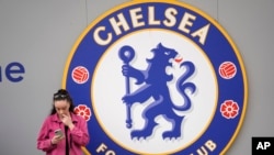 Seorang perempuan memeriksa ponselnya di luar stadion Stamford Bridge sebelum dimulainya pertandingan sepak bola Liga Inggris antara Chelsea dan Wolverhampton, di London, Sabtu, 7 Mei 2022. (Foto: AP)