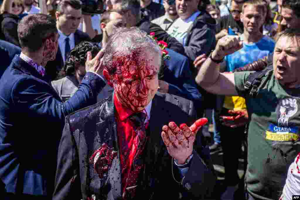 Russian Ambassador to Poland Sergey Andreev reacts after being covered with red paint during a protest prior a ceremony at the Soviet soldier war mausoleum in Warsaw, Poland, on the day of the 77th anniversary of the 1945 Soviet victory against Nazi Germany.&nbsp;